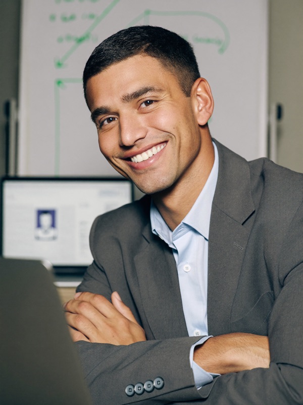 Mateo Reyes, a confident, warm man in his late thirties in a smart-casual blazer, smiling, in a modern office with a whiteboard behind him.